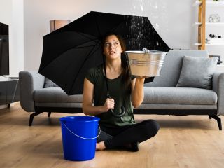 Woman holding an umbrella in a flooded home, emphasizing the need for professional flood damage restoration services.