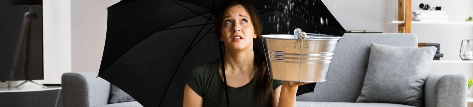 Woman holding an umbrella in a flooded home, emphasizing the need for professional flood damage restoration services.